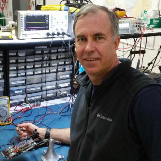 Walt Holm looking at camera while using a multimeter on a circuit board